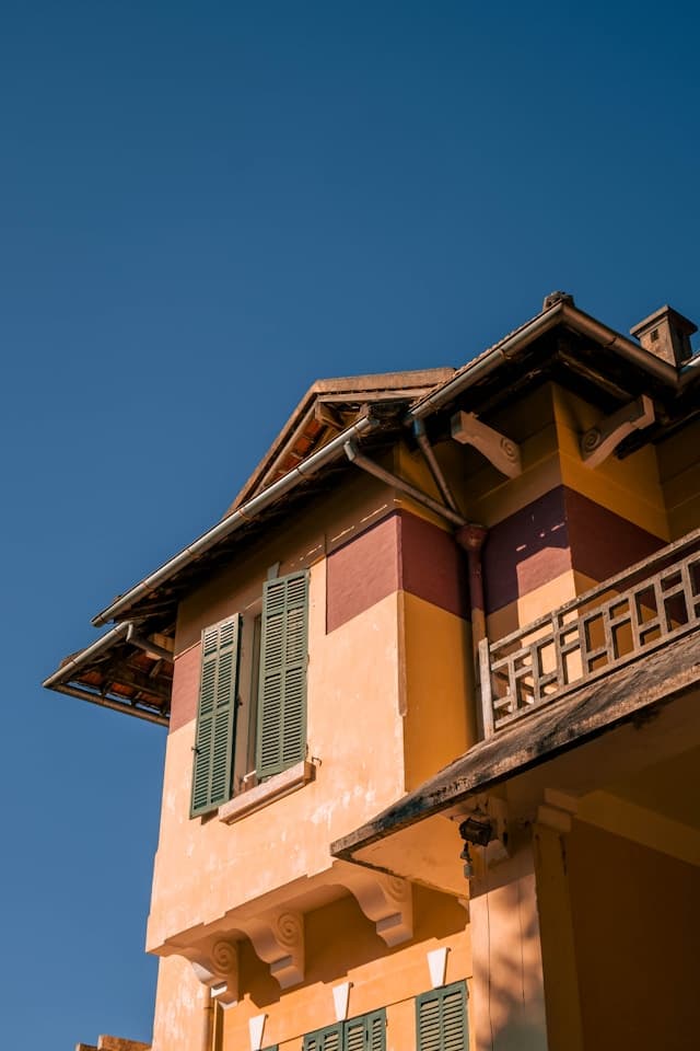 Homeowner and service specialist reviewing a home exterior and roofline in daylight.